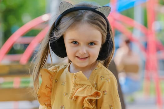 Portrait of a four-year-old girl sitting on a park bench. Close-up.