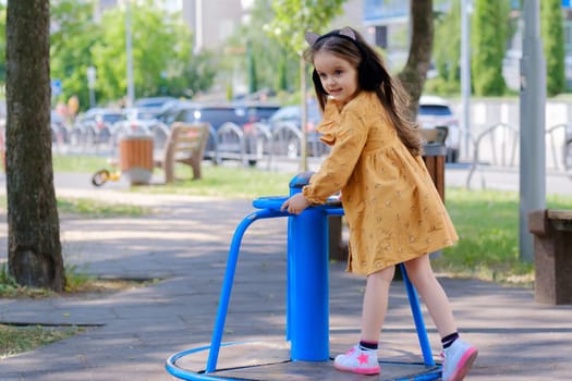 Happy little girl is playing on the playground in the park.