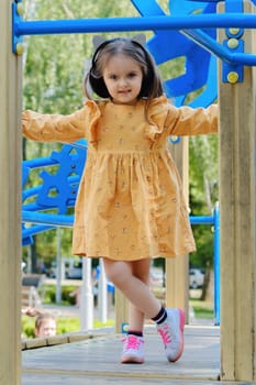 Happy little girl is playing on the playground in the park.