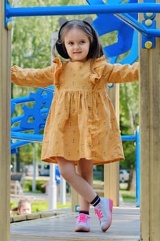 Happy little girl is playing on the playground in the park.