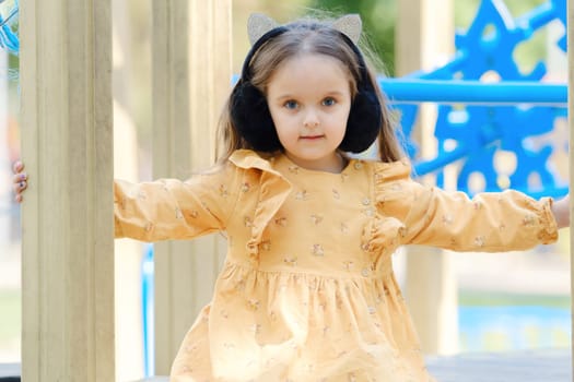 Happy little girl is playing on the playground in the park.