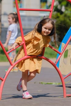 Happy little girl is playing on the playground in the park.