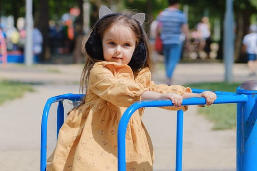 Happy little girl is playing on the playground in the park.