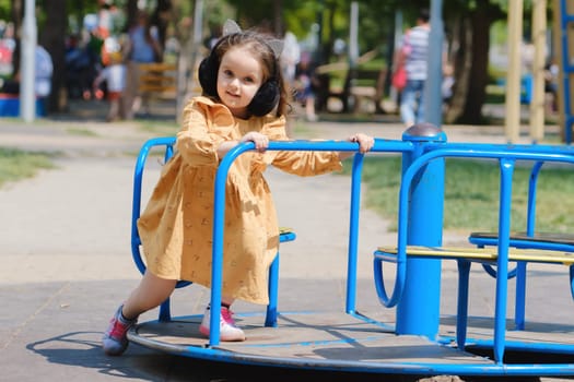 Happy little girl is playing on the playground in the park.