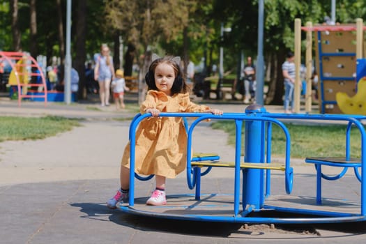 Happy little girl is playing on the playground in the park.