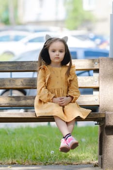 Portrait of a four-year-old girl sitting on a park bench.