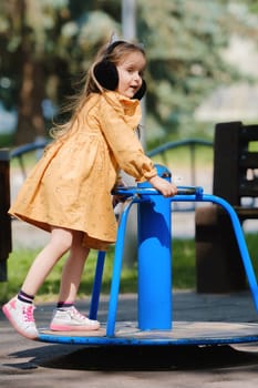 Happy little girl is playing on the playground in the park.