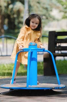 Happy little girl is playing on the playground in the park.