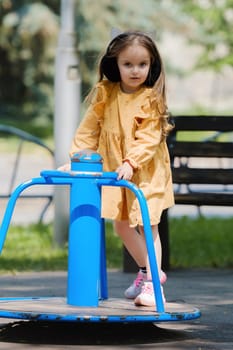 Happy little girl is playing on the playground in the park.