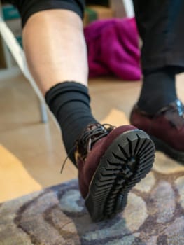 unrecognizable woman in the shop trying new shoes. Caucasian woman sitting in a shoe store while chooses new pair of italian sneakers.