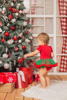 Beautiful baby in new Year costume standing near the christmas tree.