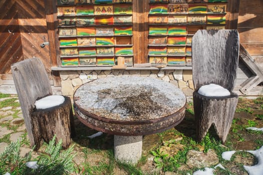 Round stone table and chairs carved from tree trunks near an alpine village