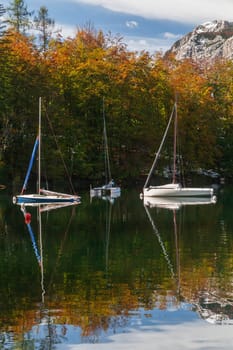 Three yachts on Lake Bohinj in Slovenia. Alps and autumn forest.
