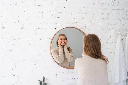 Woman looking at the mirror, making up in the morning. young millennial woman doing her morning routine at the bedroom