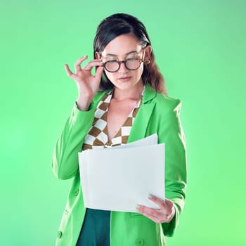 Woman in glasses reading paper isolated on green background for fashion design career, gen z resume and internship. Young person or model with retro clothes and documents review for job opportunity.