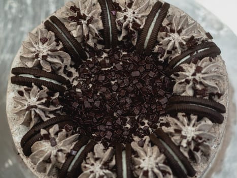 preparing brown frosted icing cup cake with cookies on top in the kitchen