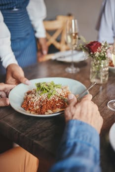 Food, restaurant and hands with a couple and waitress serving a pasta in a fine dining establishment. Date, romance and together with a senior man and woman enjoying eating on their anniversary.