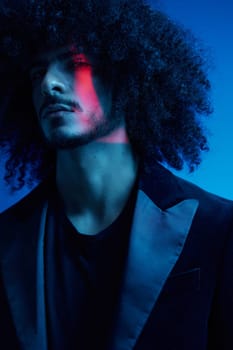 Fashion portrait of a man with curly hair on a blue background, multinational, colored light, trendy, modern concept. High quality photo