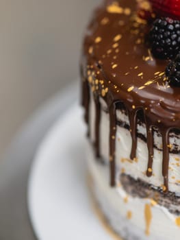 pastry chef preparing a chocolate frosted dripped icing cup cake with sweet fruit topping and golden brush strokes