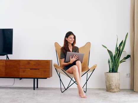 Woman student study sits on a chair with a laptop work at home smile, modern stylish interior Scandinavian lifestyle, copy space. High quality photo