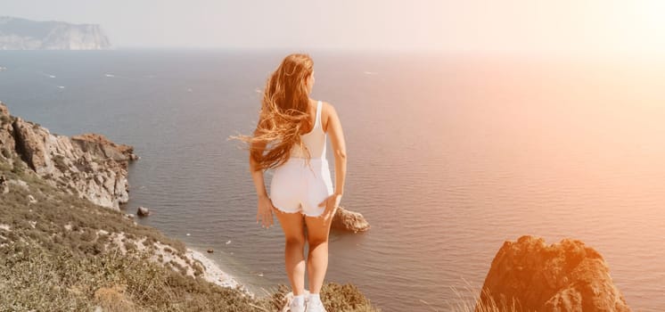 Woman travel sea. Young Happy woman in a long red dress posing on a beach near the sea on background of volcanic rocks, like in Iceland, sharing travel adventure journey