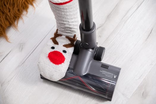 An overhead view of a foot trampling a vacuum cleaner tip. Keeping things tidy by frequently cleaning the floorboards.