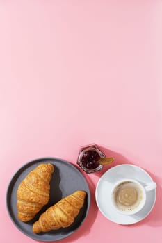 Delicious breakfast with fresh croissants, coffee and fresh berries on a pink background. copy space