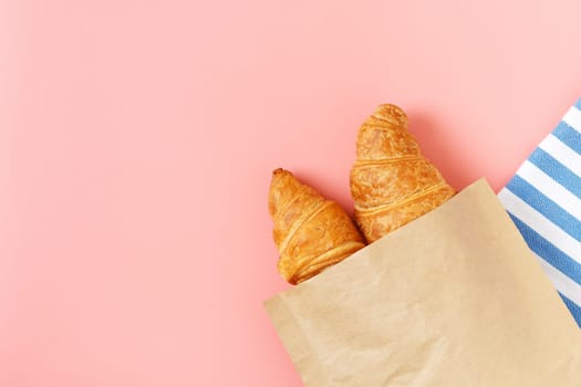 Delicious croissants in a package on a pink background. french pastries. copy space.