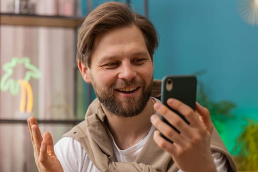 Oh my God Wow. Excited happy young man use smartphone typing browsing celebrating success winning, lottery jackpot goal achievemen, good news, victory. Caucasian guy holds mobile phone at home room