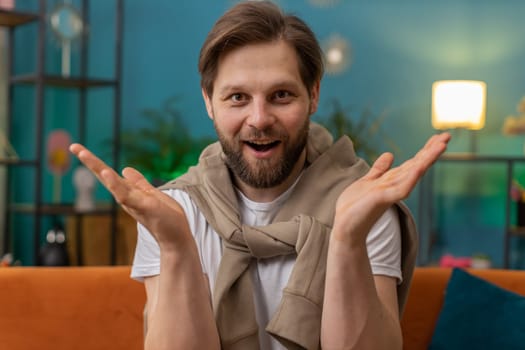 Oh my God, Wow. Excited amazed young man surprised looking at camera with big eyes, shocked by sudden victory, good win news, celebrating. Portrait of Caucasian guy at home apartment room on sofa