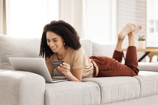 Laptop, ecommerce and customer with a black woman online shopping using her credit card in the house. Computer, living room and payment with a female consumer using technology to shop on the sofa.
