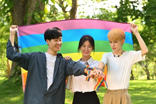 Young people celebrating together stacking hands outdoor. Supporters of the LGBT community, shooting of equality social.