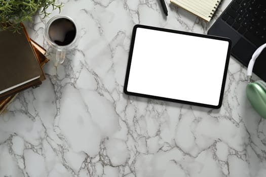 Top view of digital tablet with white empty screen, headphone and coffee cup on marble background.