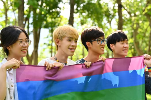 Group of young activist holding pride rainbow flag, supporting LGBTQ community and shooting of equality social.