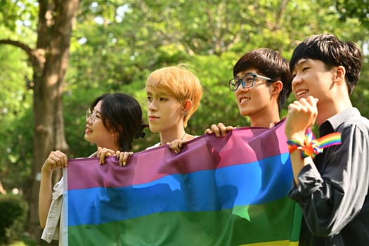 Group of young activist holding pride rainbow flag, supporting LGBTQ community and shooting of equality social.