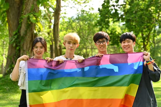 Group of young activist holding pride rainbow flag, supporting LGBTQ community and shooting of equality social.