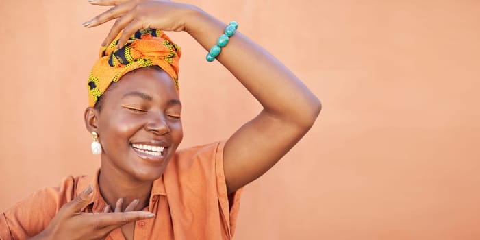 African, fashion and face of black woman on orange wall background with natural beauty, makeup and smile. Culture, hands and girl in Nigeria with designer jewelry, exotic cosmetics and head scarf.