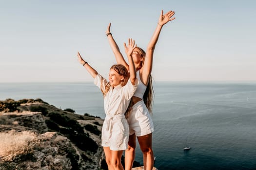 Close up portrait of mom and her teenage daughter hugging and smiling together over sunset sea view. Beautiful woman relaxing with her child.