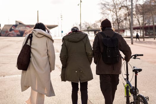 rear view of three young friends walking through the city, concept of friendship and modern urban lifestyle