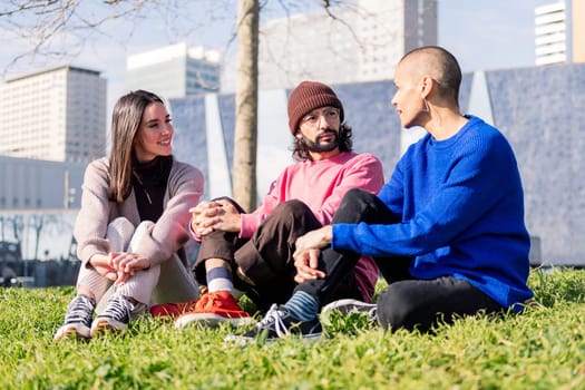 three young friends enjoying conversation in a sunny day at the city park, concept of friendship and urban lifestyle