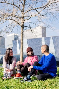 three young friends enjoying conversation in a sunny day at the city park, concept of friendship and urban lifestyle
