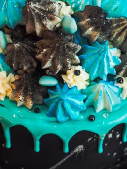 frosted black painted cup cake with blue turquoise dripping and colored handmade meringue topping studio white isolated background