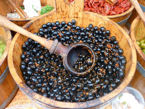 Black olives in wooden barrels on an olives stall in London Borough market