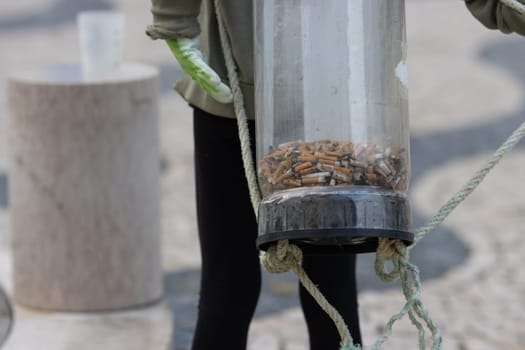 Activist wears a container on their back to store cigarette bulls abandoned on the street. Mid shot