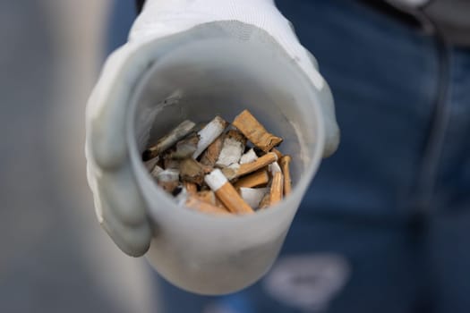 Enthusiast shows a glass of dropped cigarette bulls. Mid shot