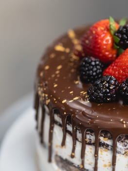 pastry chef preparing a chocolate frosted dripped icing cup cake with sweet fruit topping and golden brush strokes