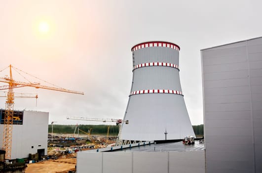 Construction of a nuclear power plant. Tower cranes on the background of the cooling tower.