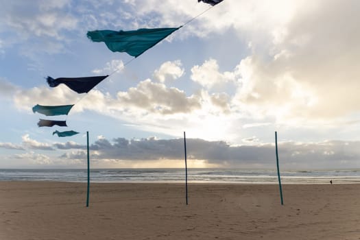 Blue and dark blue cloth fluttering on a rope on a clean beach at an early sunset. Mid shot