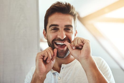 My teeth makes a great smile. Cropped portrait of a handsome young man flossing his teeth in the mirror at home