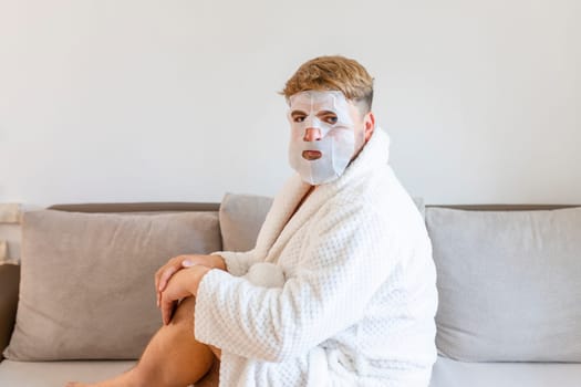 Funny man having fun at home using the face mask for better mood feeling awesome. Portrait of guy doing cosmetic procedures. People skin care concept .